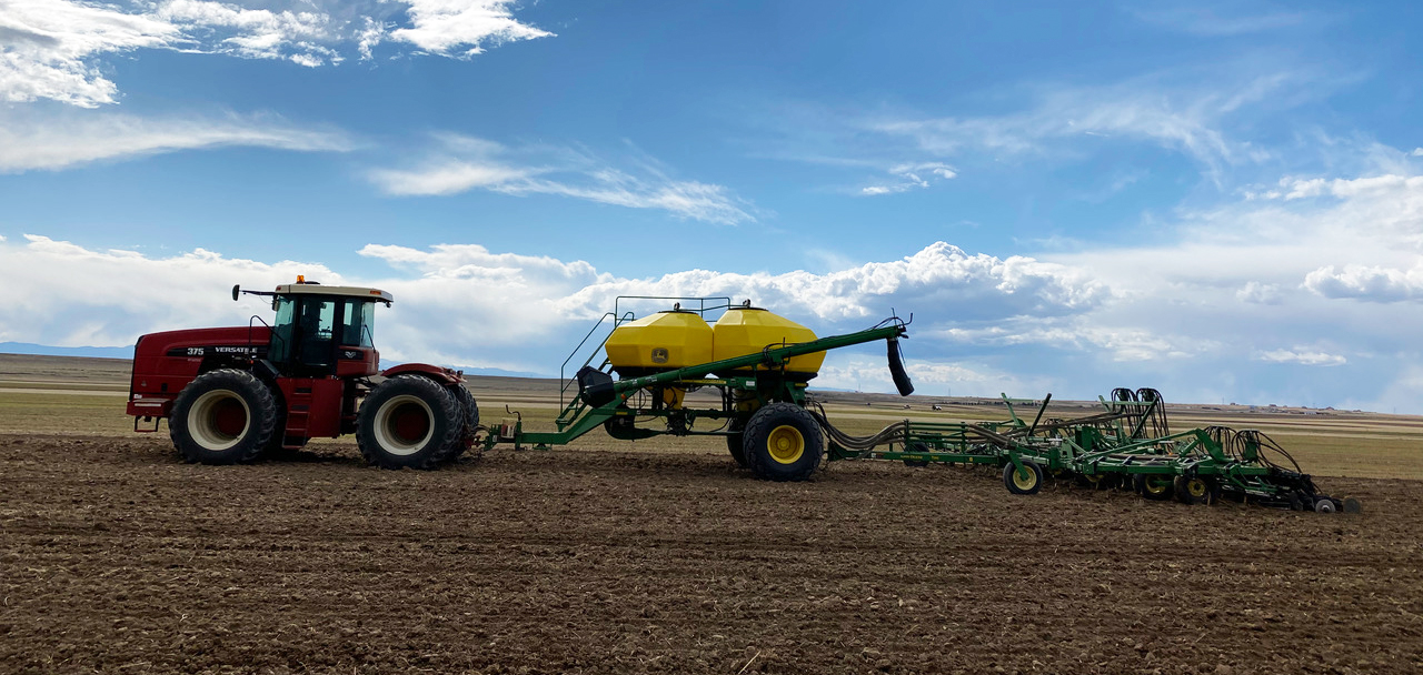 side photo of a tractor seeding field with millet
